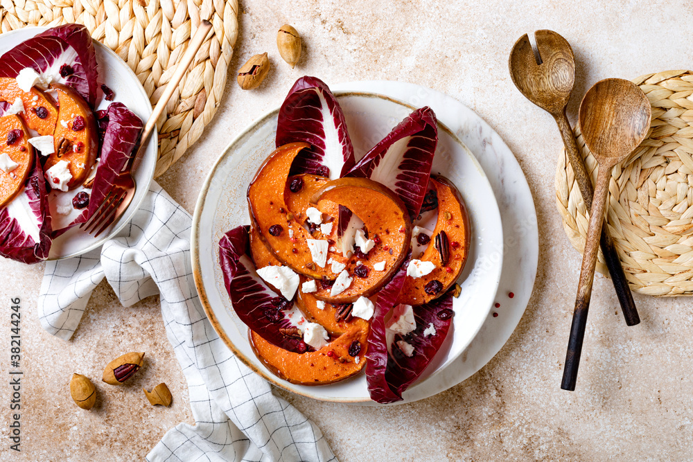 Roasted pumpkin salad with radicchio leaves, feta cheese, nuts and cranberries. Thanksgiving side dish dinner recipe. Healthy seasonal fall or autumn food