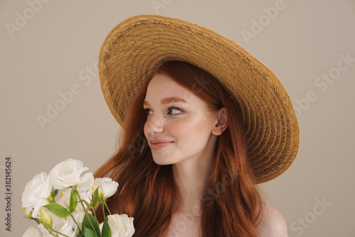 Photo of smiling redhead shirtless girl posing with white flowers © Drobot Dean