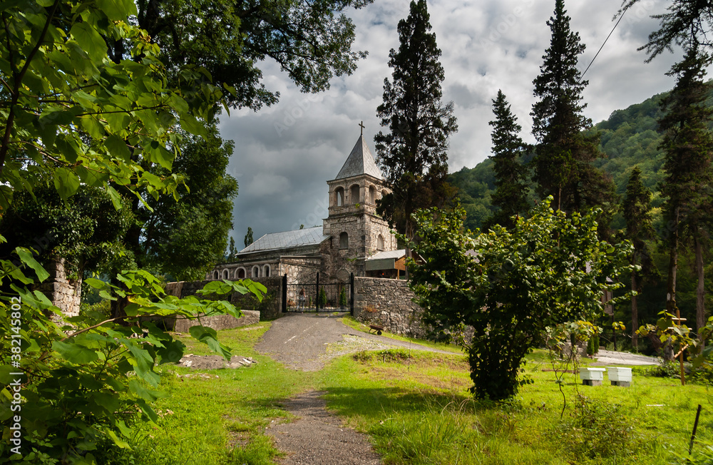 The temple on the hill, built of brown stone surrounded by forest and green wooded mountains. Abkhazia, the village of Kamany, The burial place of St. John Chrysostom in 407