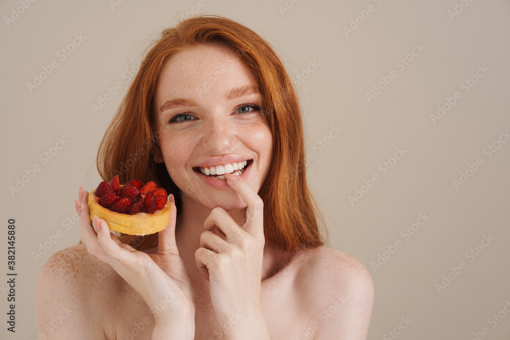 Photo of cheerful redhead shirtless girl posing with cake Photo of cheerful redhead shirtless girl posing with cake