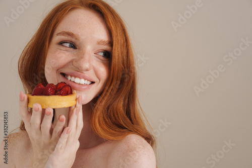 Photo of cheerful redhead shirtless girl posing with cake