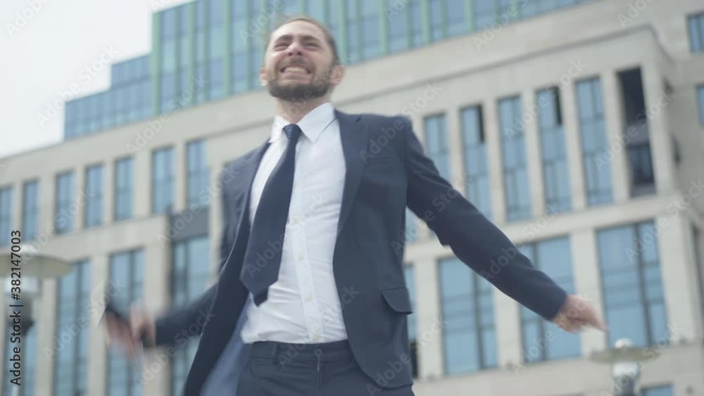 Happy Caucasian man hanging up phone and making victory gesture. Portrait of excited young businessman having successful business deal. Handsome entrepreneur rejoicing outdoors in urban city. Happy Caucasian man hanging up phone and making victory gesture. Portrait of excited young businessman having successful business deal. Handsome entrepreneur rejoicing outdoors in urban city.