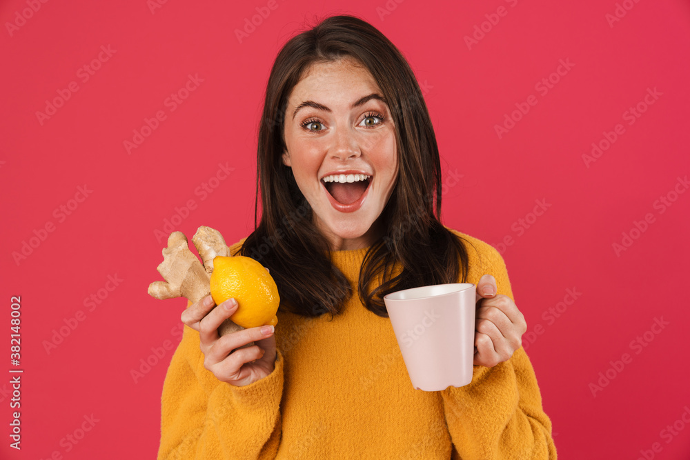 Image of excited girl holding lemon and ginger while drinking tea Image of excited girl holding lemon and ginger while drinking tea