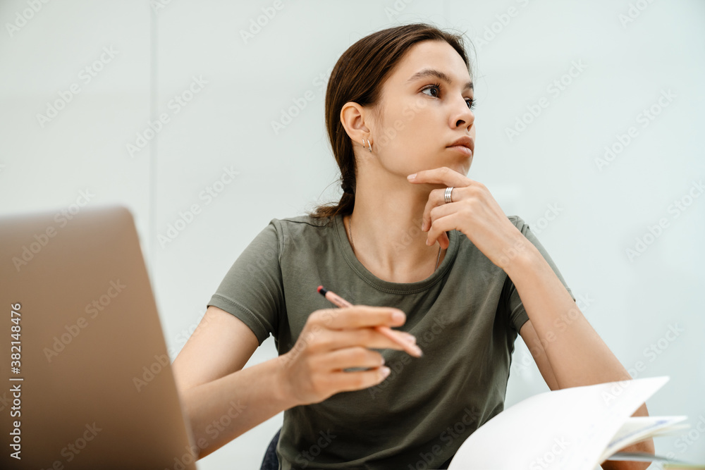 Image of thinking student girl doing homework with laptop Image of thinking student girl doing homework with laptop
