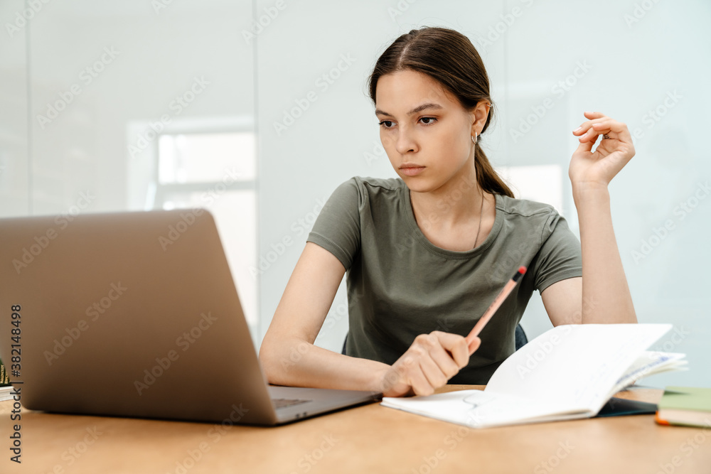 Image of focused student girl doing homework with laptop Image of focused student girl doing homework with laptop