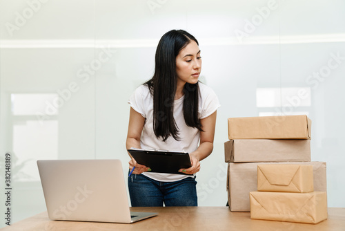 Photo of asian delivery assistance working with packages and laptop © Drobot Dean