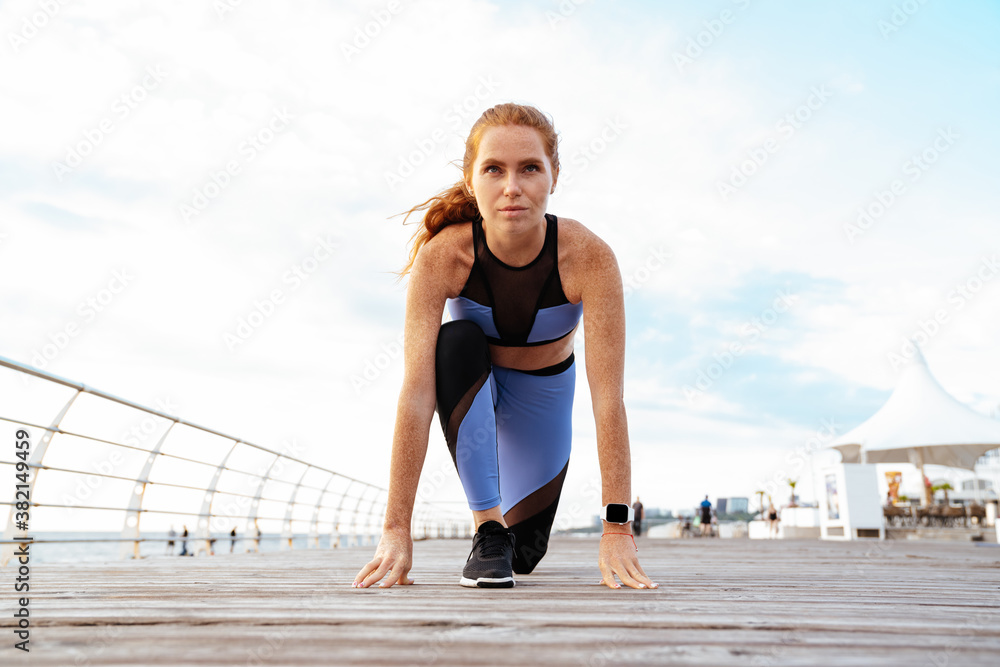 Image of redhead athletic sportswoman doing exercise while working out