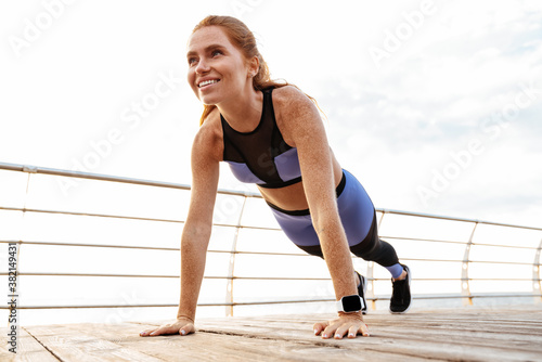 Image of redhead smiling sportswoman doing exercise while working out © Drobot Dean