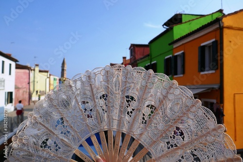 Souvenir lace fan on the background of colorful buildings of Burano island, Venice, Italy 