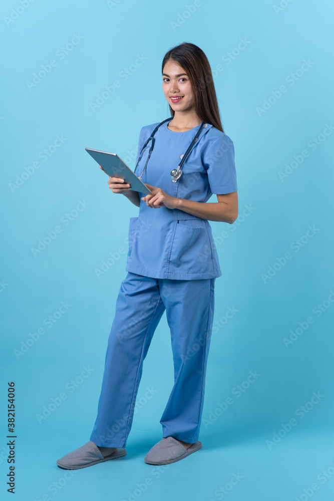 Young woman in nurse uniform standing and smile isolated on light blue background. Young woman in nurse uniform standing and smile isolated on light blue background.