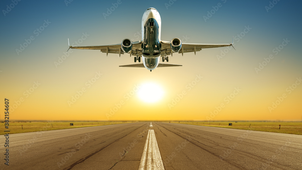 commercial airplane takes off against a sunset