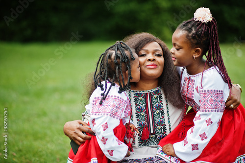 African mother with daugters in traditional clothes at park. photo