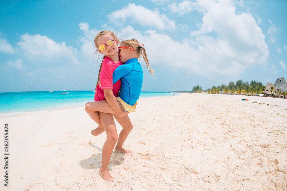 Two little happy girls have a lot of fun at tropical beach playing together Two little happy girls have a lot of fun at tropical beach playing together