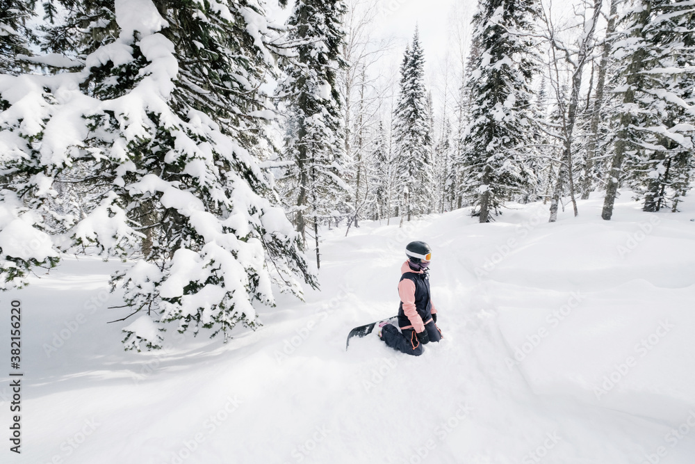 snowboarder woman rest during snowboarding in winter snow-covered fur forest, fresh snow powder, freestyle freeride on sunny winter day