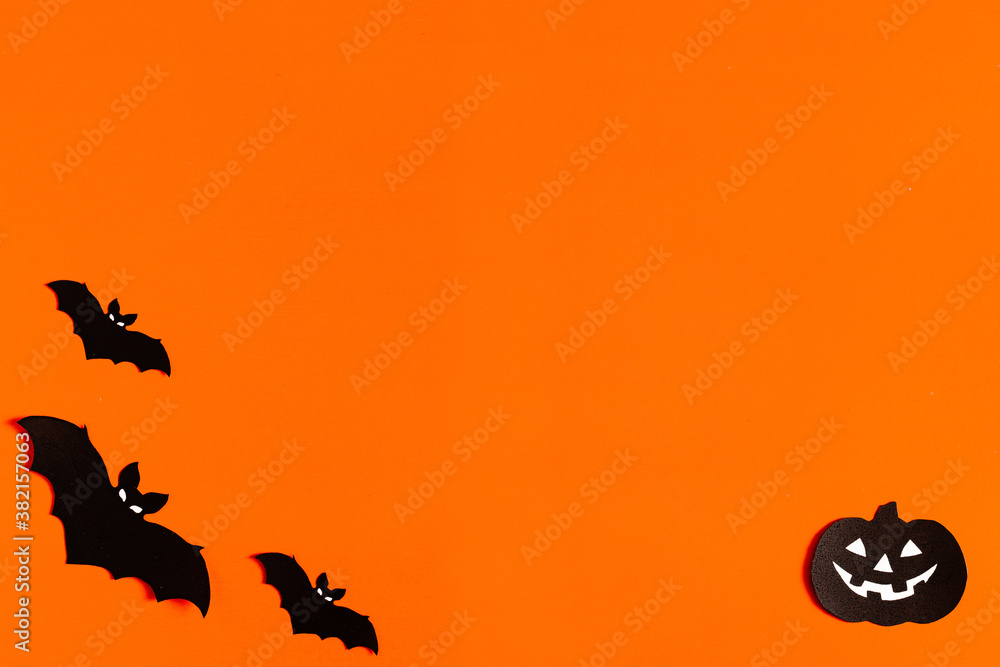 silhouettes of bats and pumpkins made of black paper on an orange background, Halloween concept, ready-made layout with space for text, copy space. Flat lay for your design