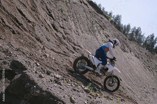 Rider climbing sand mountain on off-road cross motorcycle