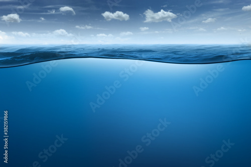 Underwater sea surface and deep blue sea against blue sky and soft clouds summer background photo