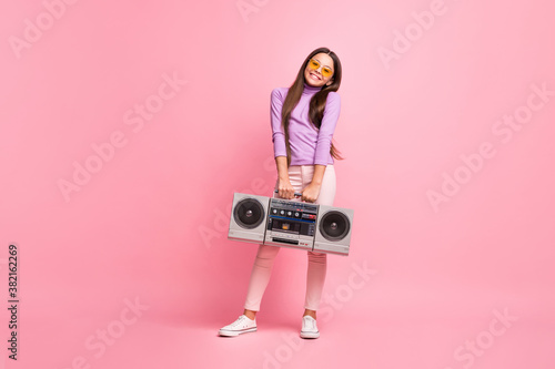 Full length photo of little kid girl hold cassette retro boom box wear purple pants isolated over pastel color background