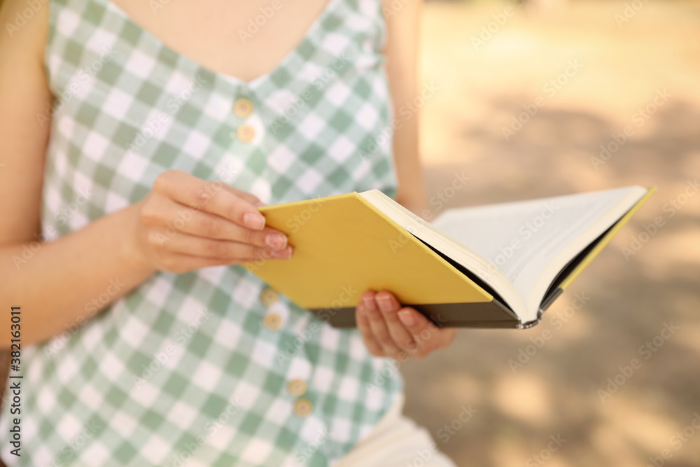 Young woman reading book outdoors, closeup view Young woman reading book outdoors, closeup view
