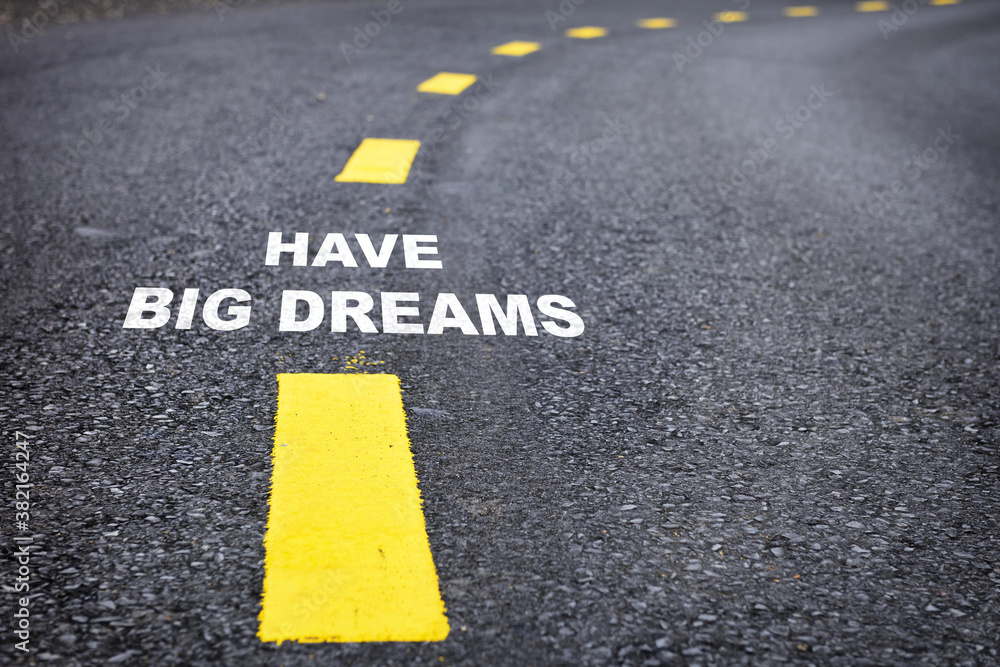 Have big dreams words on asphalt road surface with marking lines. Inspiration and motivation concept and effort idea