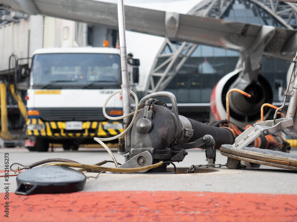 Fototapeta premium Jet A1 gasoline refueling to aircraft during transit. nozzle connect with ground tank, pump to service truck then transfer to airplane with red caution sign.
