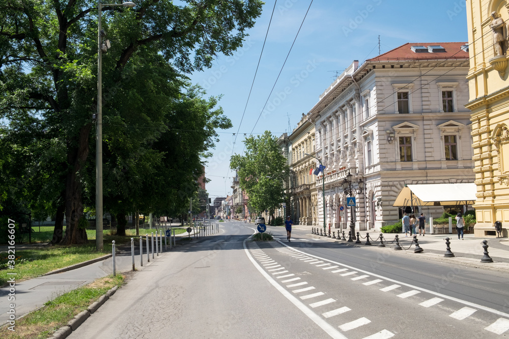 The slow holiday traffic on the road and the empty street in the historical center of Szeged, Hungary known for its beautiful old traditional architecture