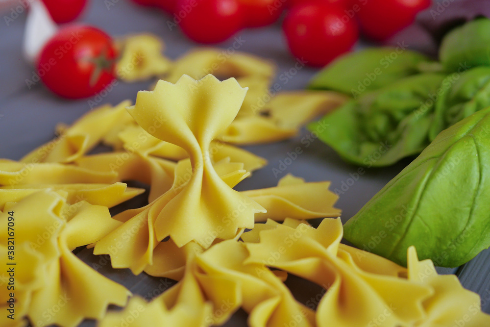Homemade farfalle close up on a background of cherry tomatoes and basil