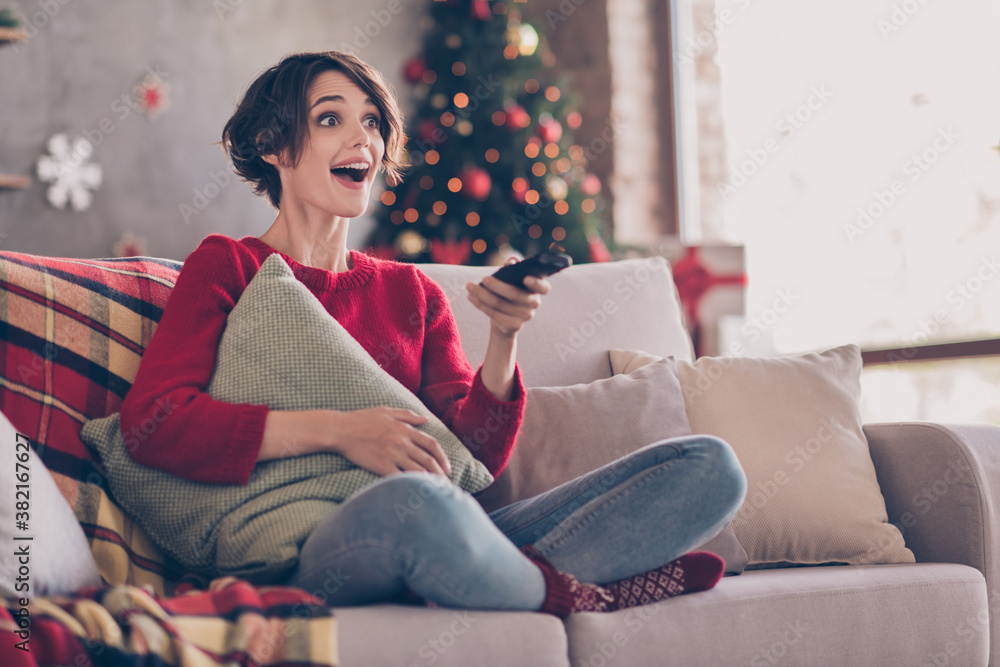 Photo of charming young lady hold remote control cuddle pillow sitting sofa open mouth wear red sweater jeans socks indoors Photo of charming young lady hold remote control cuddle pillow sitting sofa open mouth wear red sweater jeans socks indoors