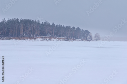 Snow-covered bank of a frozen river © Larisa