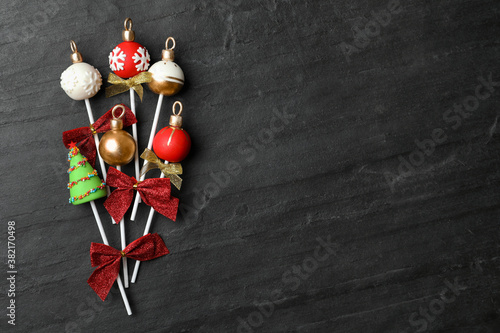 Delicious Christmas themed cake pops on black table, flat lay. Space for text