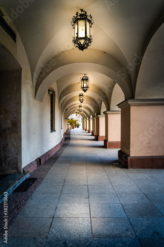 Arcades or archway with long corridor illuminated by vintage lanterns. Townhall building on city square in Kielce, Poland