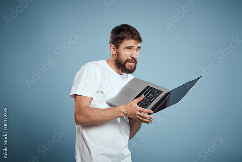 Emotional man with laptop in hands on blue background monitor keyboard internet model cropped view