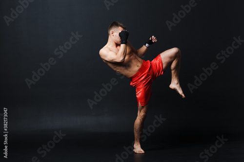 Sportsman muay thai man boxer stance ad knee kick at black background © primipil