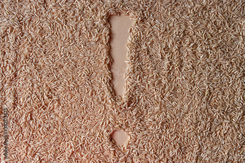 an exclamation mark sign! on a brown rice background on plywood