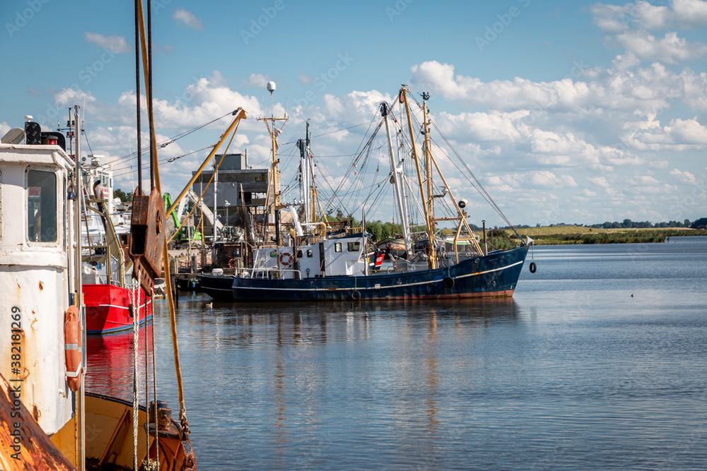 Fishing boats with shrimps on the river Reitdiep and Zoutkamperril in the harbor of Zoutkamp on a summer day with blue sky and white clouds