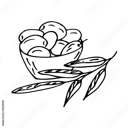 A bowl of olives, next to the bowl is an olive branch.