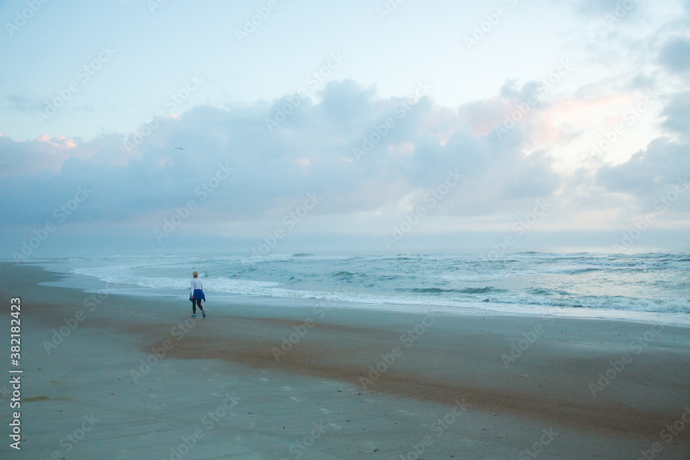 A lone beach walker on the  sand beach on Amelia Island, Florida.