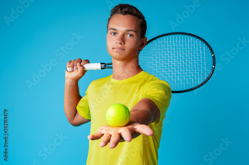 Young man tennis player in sportswear posing against blue background © fotofabrika