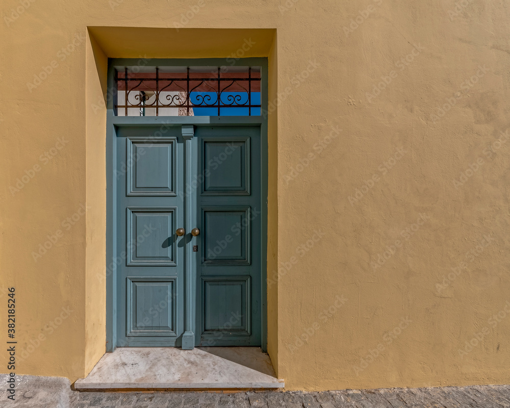 Fototapeta premium painted wooden external door and colorful wall by the sidewalk, Athens Greece. Space for text