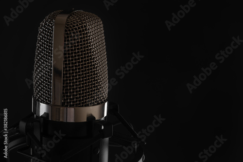 Studio condenser microphone for recording voices, isolated on black background. Copy space on right. Music concept.