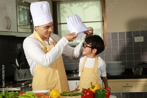 Father dress up his son to be chef in ketchen photo