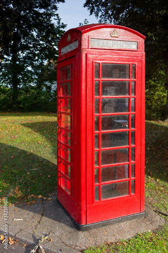 Traditional red telephone box in full sun in a park in the United Kingdom