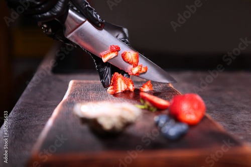 Strawberries are cut into small pieces. Preparation of berry sauce for oysters. Unrecognizable photo. Close up.