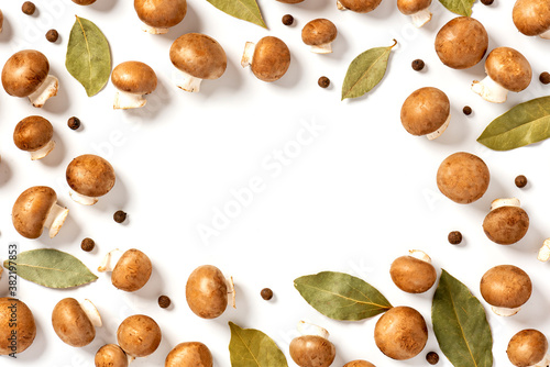 Lots of brown champignons, bay leaves and peppers on a white background top view. Flat lay. Free space for text. Pattern of brown mushrooms and spices. Mushroom cooking