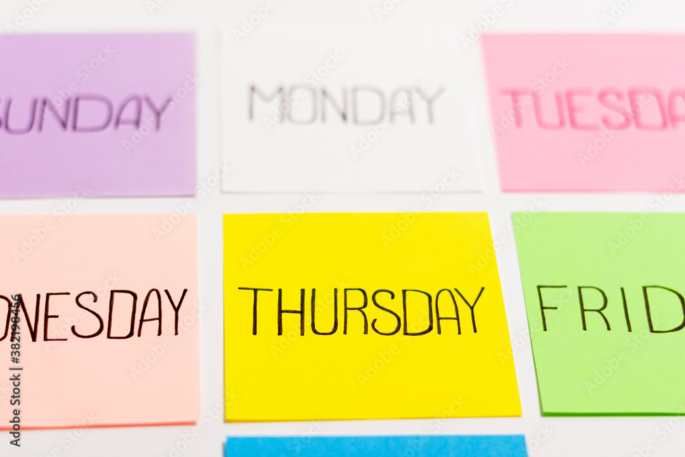 Sheets of paper of different colors are arranged in a straight tile. Each piece of paper has the name of one day of the week written on it. Sheets of paper of different colors are arranged in a straight tile. Each piece of paper has the name of one day of the week written on it.