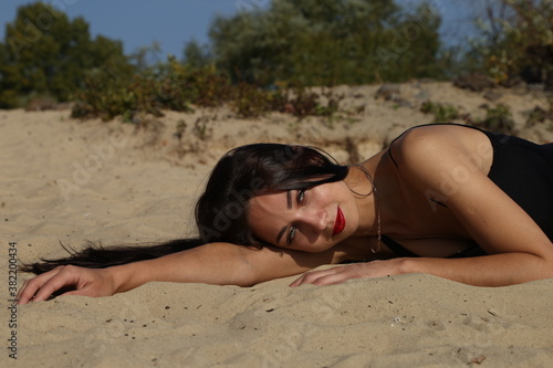 young slender brunette is lying on the sand