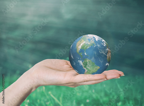 Hand Holding Earth In Lush Green Environment With Sunlight - Caring For The Environment Concept