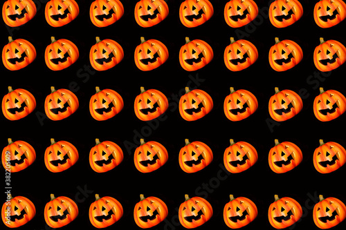 Pattern. On a black background, a lot of pumpkins with a carved smile. Pumpkins standing in glad. Halloween celebration concept.