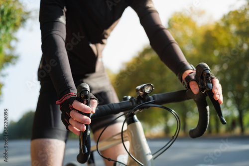 Fototapeta Naklejka Na Ścianę i Meble -  Hands of a cyclist resting on road bike handlebars. Cycling, bicycle sport training outdoors