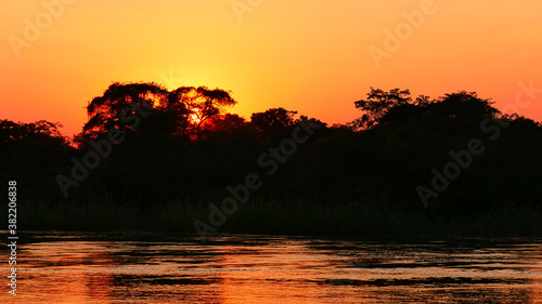 Beautiful sunset over peaceful Okavango River with evening sun shining through the trees near Divundu in Bwabwata National Park, Namibia, Africa. photo